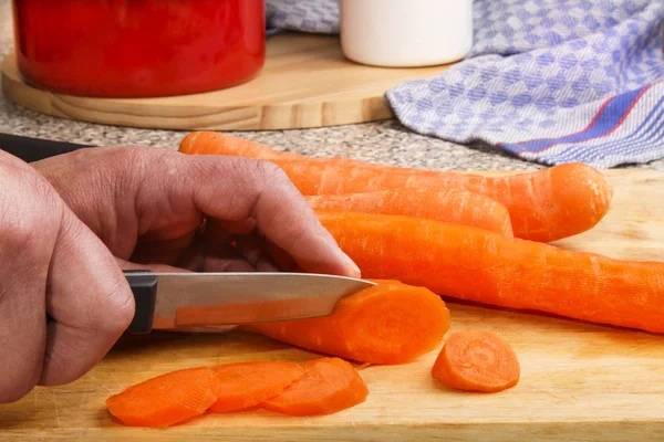 Female chef is cutting carrot into slices — Stock Photo, Image