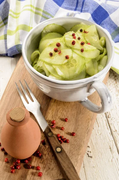 Komkommer salade in een grijze cup op houten plank — Stockfoto