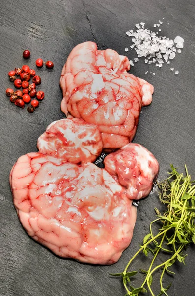 Raw pig brain, red peppercorn, coarse salt and thyme on slate — Stock Photo, Image