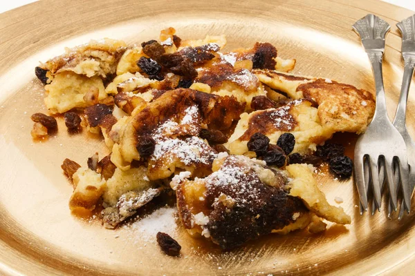 Kaiserschmarrn con pasas y azúcar en polvo sobre un color dorado —  Fotos de Stock