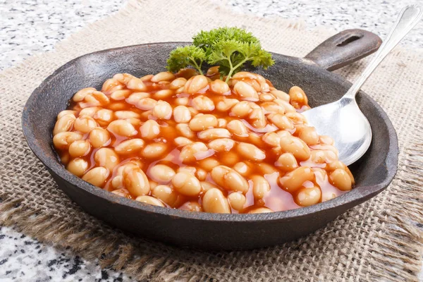 Warm baked beans in tomato sauce served in a cast iron pan — Stock Photo, Image