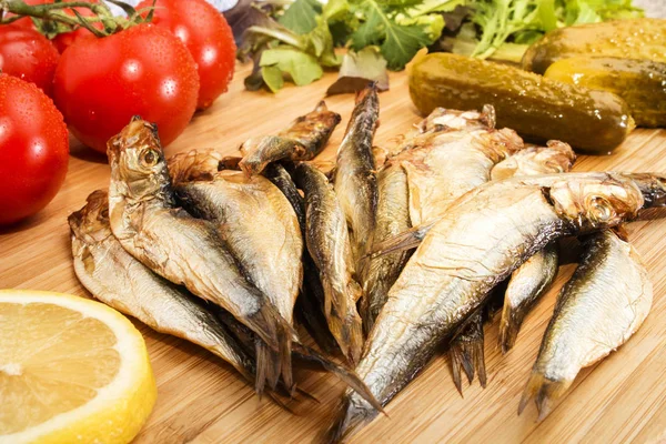 Smoked sprats with salad, tomatoes, a slice of lemon and gherkin — Stock Photo, Image
