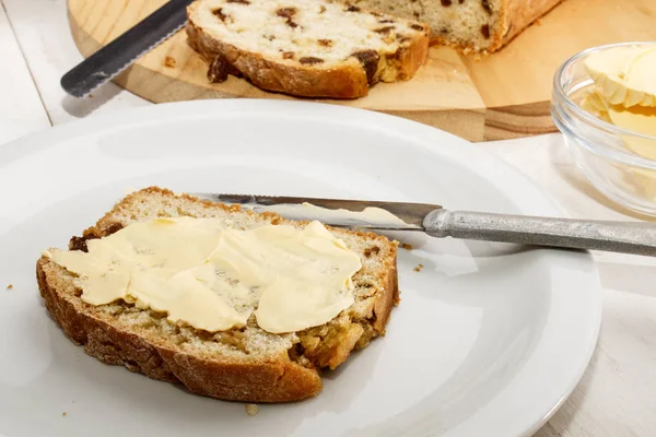 Хлеб с изюмом с маслом на белой тарелке — стоковое фото
