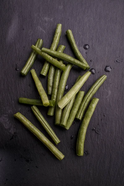 スレート上のぬれた緑の豆と水を削除します。 — ストック写真