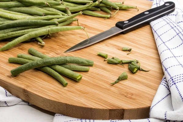 Skära gröna bönor på en träskiva — Stockfoto