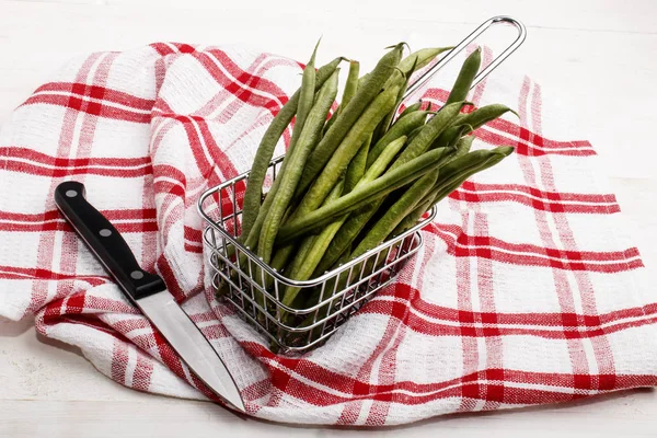 Green beans in a metal basket and a knife to cut — Stock Photo, Image