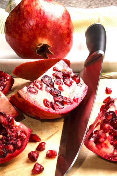 Sliced pomegranate and big kitchen knife — Stock Photo, Image