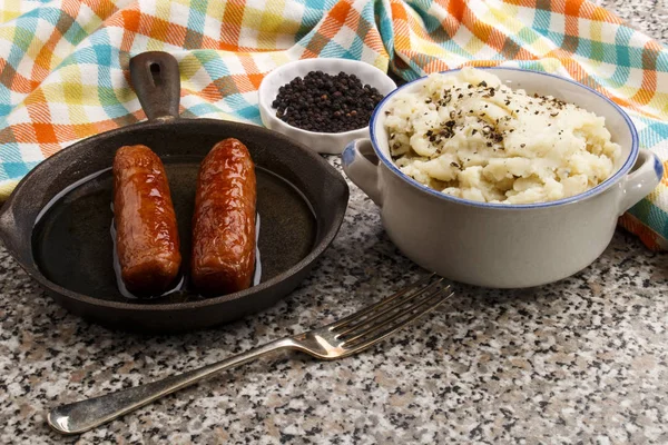 Peppered mashed potato in a bowl and sausages — Stock Photo, Image
