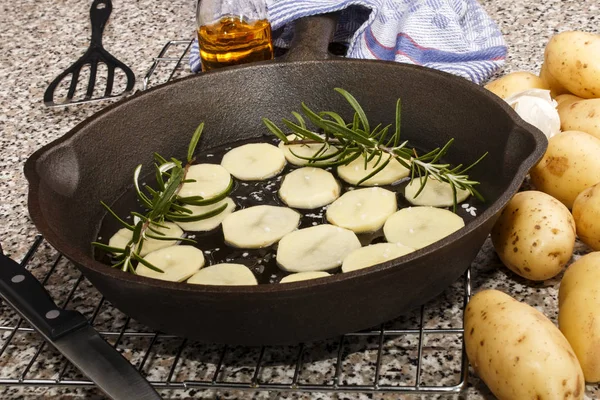 Gesneden aardappel met rozemarijn in een gietijzeren pan — Stockfoto
