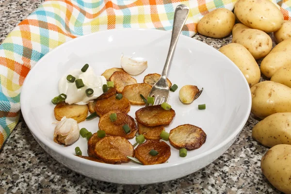 Fried potatoes, served with sour cream, roasted garlic and sprin — Stock Photo, Image