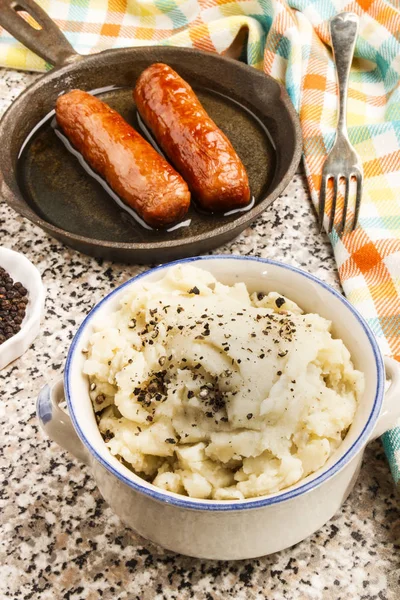Mashed potato with crushed black peppercorn and irish sausages — Stock Photo, Image