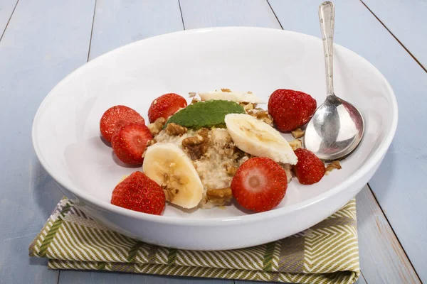Gesundes Frühstück mit Haferflocken, Walnüssen, Erdbeeren und Minzblättern — Stockfoto