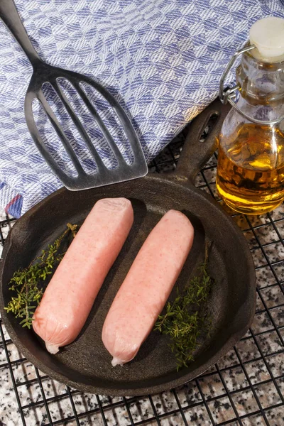 Raw british sausages with herbs in a cast iron pan — Stock Photo, Image