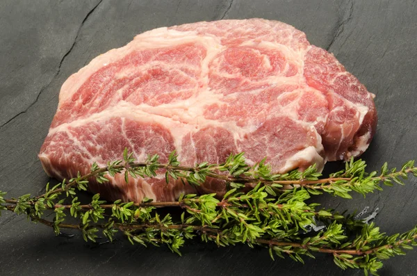 Slice raw pork neck with thyme on slate — Stock Photo, Image