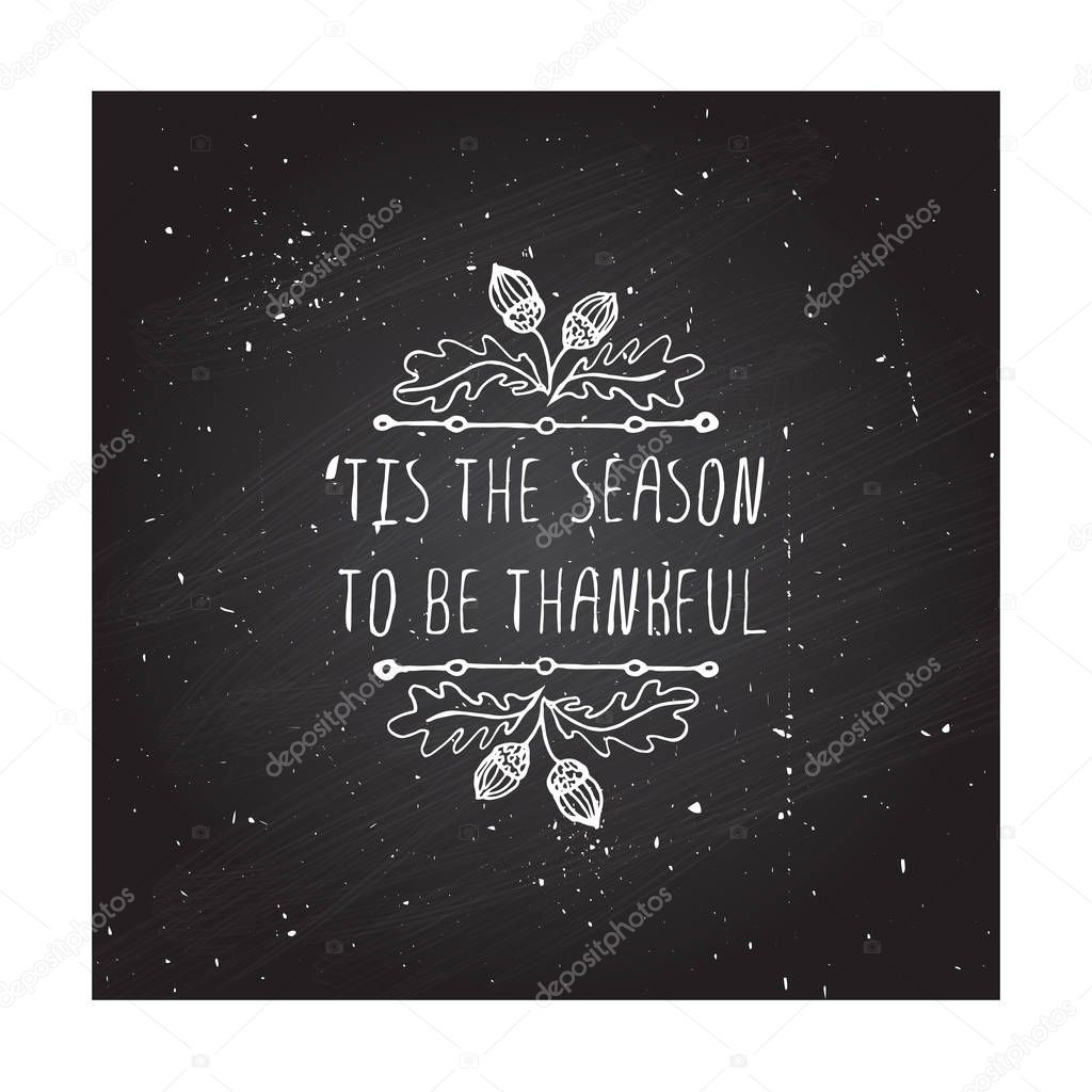Handdrawn thanksgiving label with acorns and text on chalkboard background. Tis the season to be thankful.