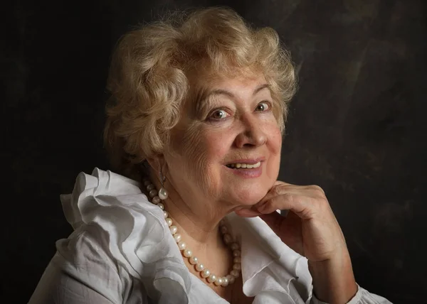 Portrait of an old smiling woman on a black art background in the studi