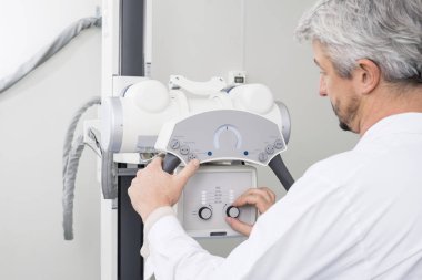 Erkek radyolog röntgen cihazı üzerindeki denetimleri ayarlama