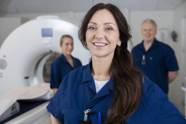 Smiling Female Radiologist With Colleagues Standing By MRI Machi clipart