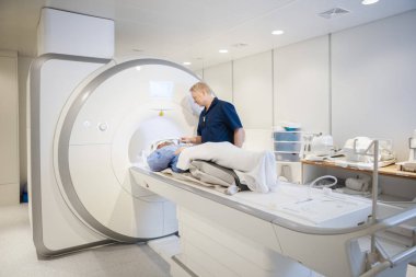 Doktor bobin MRI tarama geçiren kadın hasta başının üstüne koyarak