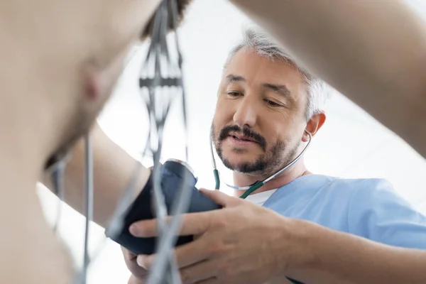 Médico que mede a pressão arterial do paciente masculino — Fotografia de Stock