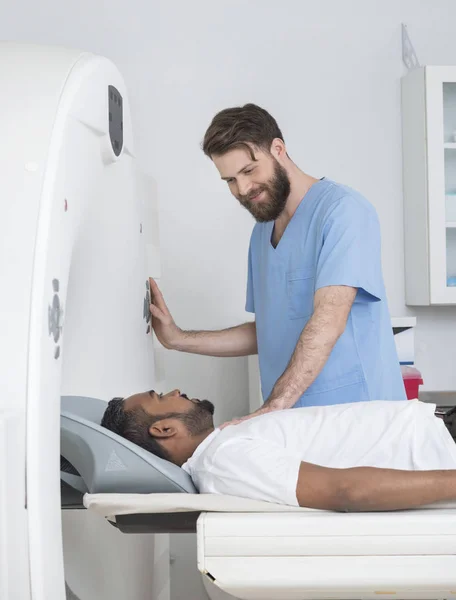 Médico jovem prestes a iniciar a tomografia computadorizada no paciente masculino — Fotografia de Stock
