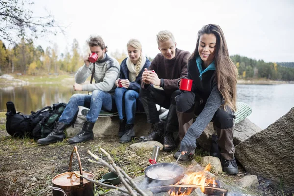 Woman Cooking Food On Campfire With Friends In Background — Stock Photo, Image