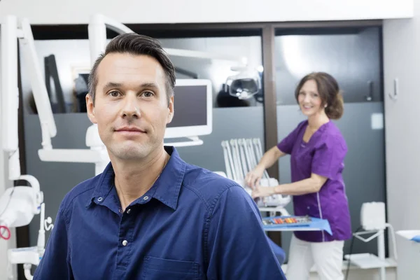 Selbstbewusste Zahnärztin mit Assistentin lächelt in Klinik — Stockfoto
