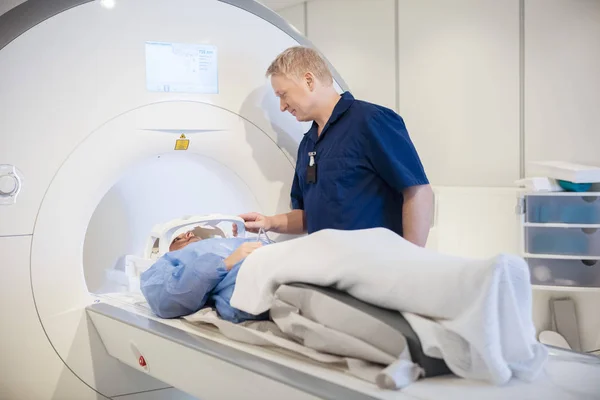 Ο γιατρός, βάζοντας το πηνίο στο κεφάλι τους ασθενείς που υποβάλλονται σε μαγνητική τομογραφία — Φωτογραφία Αρχείου