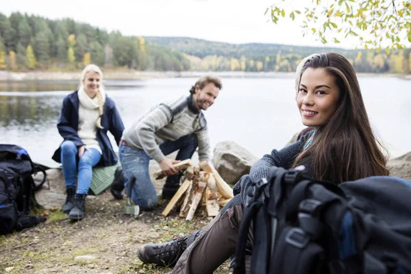 Femme avec des amis préparation de feu de joie sur le bord du lac — Photo