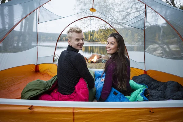 Casal sentado na tenda durante o acampamento à beira do lago — Fotografia de Stock