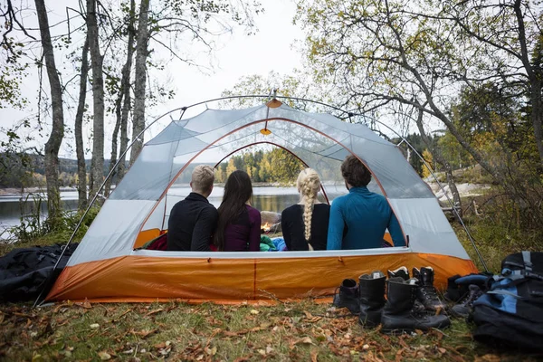 Jonge vrienden zitten In de Tent op de oever van het meer — Stockfoto