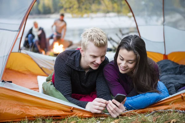 Young Couple Using Mobile Phone In Tent — Stock Photo, Image