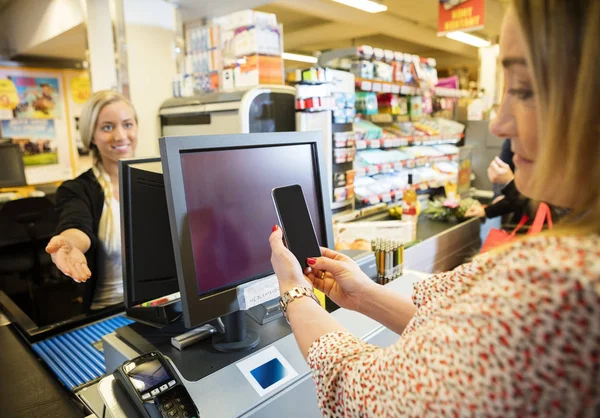 Caixa Gesturing Enquanto Cliente Feminino Fazendo Pagamento NFC — Fotografia de Stock