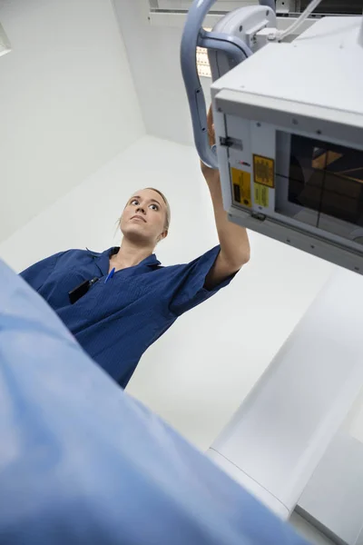 Blick in den niedrigen Winkel des Radiologen, der das Röntgengerät über der Patientin justiert — Stockfoto
