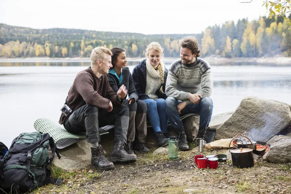 Amigos hablando en la orilla del lago durante el camping —  Fotos de Stock