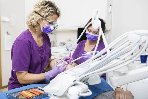 Dentistas trabalhando em jovens mulheres dentes na clínica — Fotografia de Stock