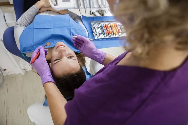 Herramientas de sujeción del dentista mientras examina a paciente joven —  Fotos de Stock