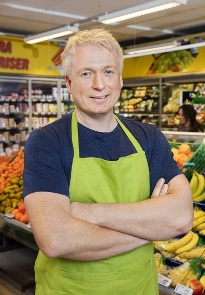 Säljare med händerna vikas står i mataffären — Stockfoto