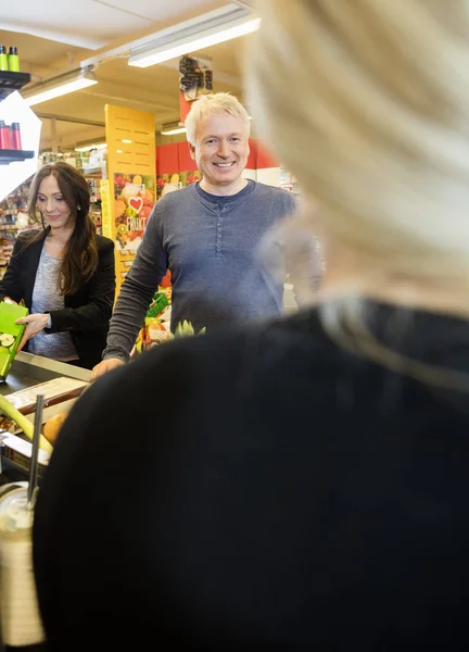 Clientes sorrindo no balcão de check-out — Fotografia de Stock