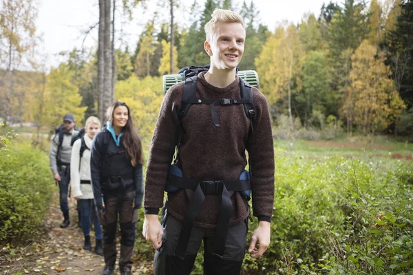 Uomo sorridente con gli amici Escursioni sul sentiero forestale — Foto Stock