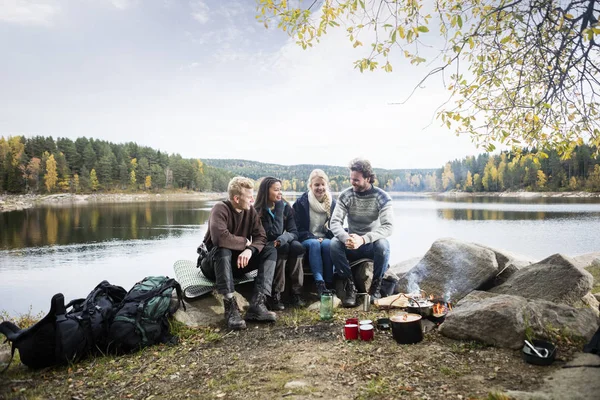 Přátelé sedící na břehu jezera během kempování — Stock fotografie