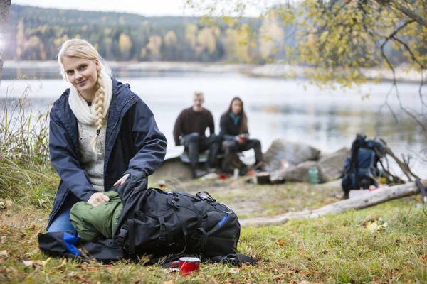 Jovem mulher desembalando mochila no acampamento — Fotografia de Stock