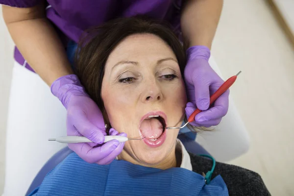 Paziente con bocca aperta esaminata dagli strumenti di detenzione del dentista — Foto Stock