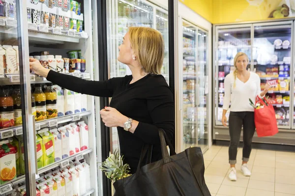 Жінка вибирає сокові пакети в продуктовому магазині — стокове фото