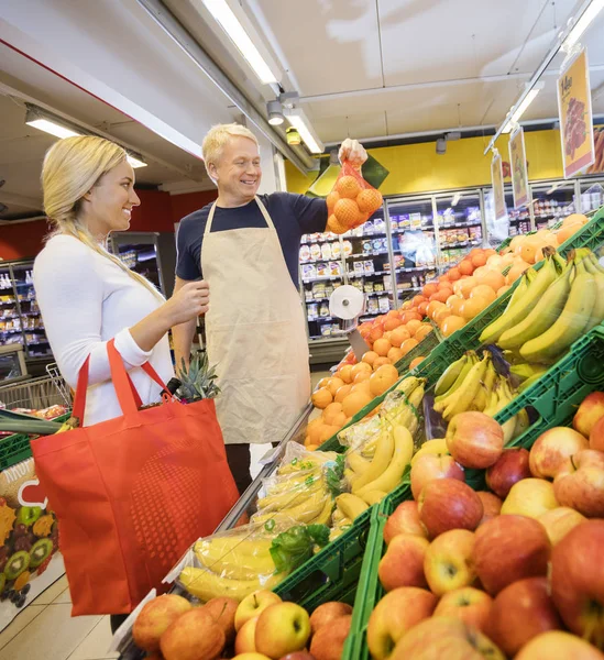 Vendedor mostrando laranjas para cliente feminino no supermercado — Fotografia de Stock