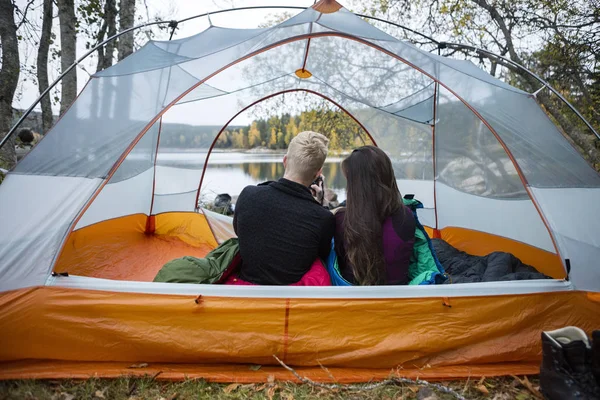 Młoda para cieszy widok jeziora z namiotu — Zdjęcie stockowe