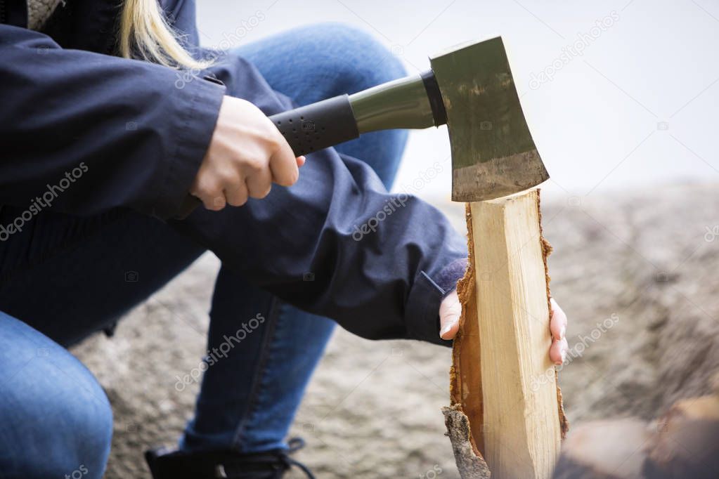 Woman Cutting Wood For Bonfire On Campsite