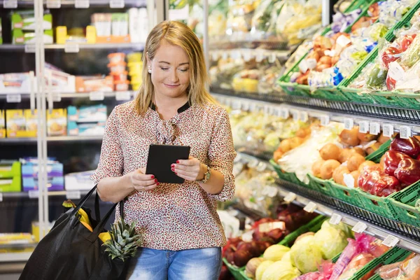 Customer Using Digital Tablet While Shopping In Grocery Store