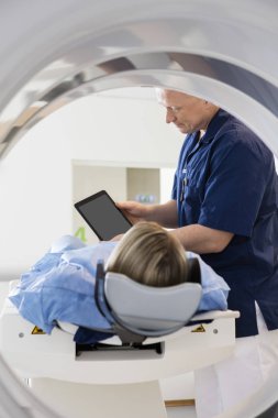 Doctor Showing Digital Tablet To Patient Undergoing CT Scan clipart