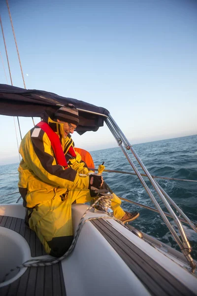 Uomo manovella un verricello sulla barca a vela in mare — Foto Stock